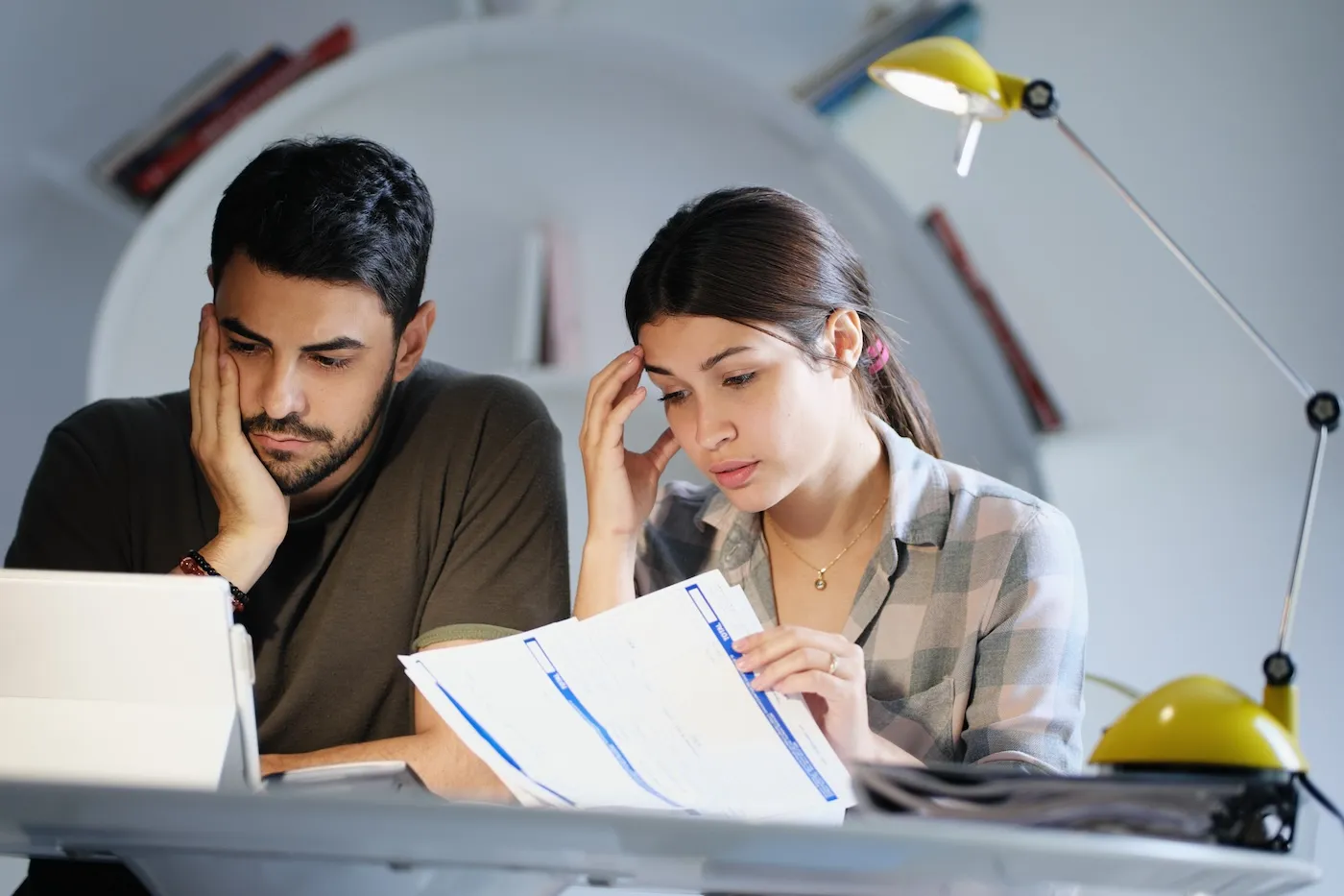 Young couple reviewing invoices and doing taxes, concerned about tax fraud.