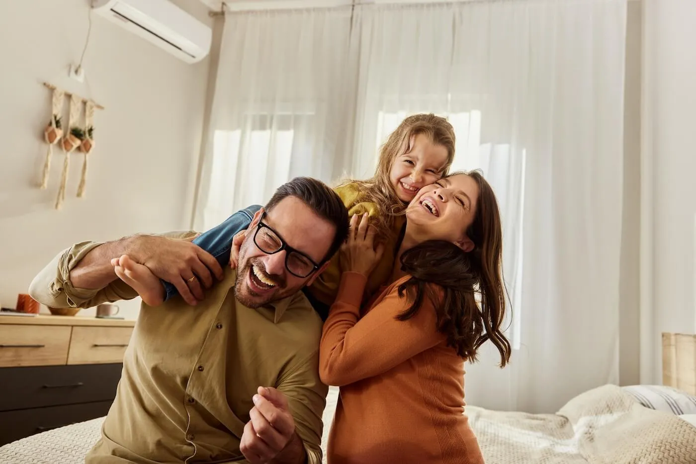 A happy family of three playing in the bedroom