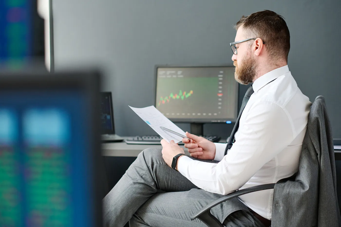 Young adult man sitting at desk in office working on brokerage account.