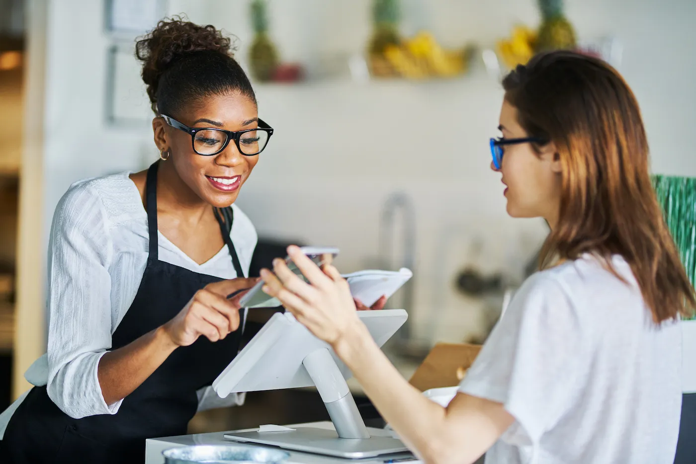 A store clerk helping a customer using an online coupon from smartphone app at a store