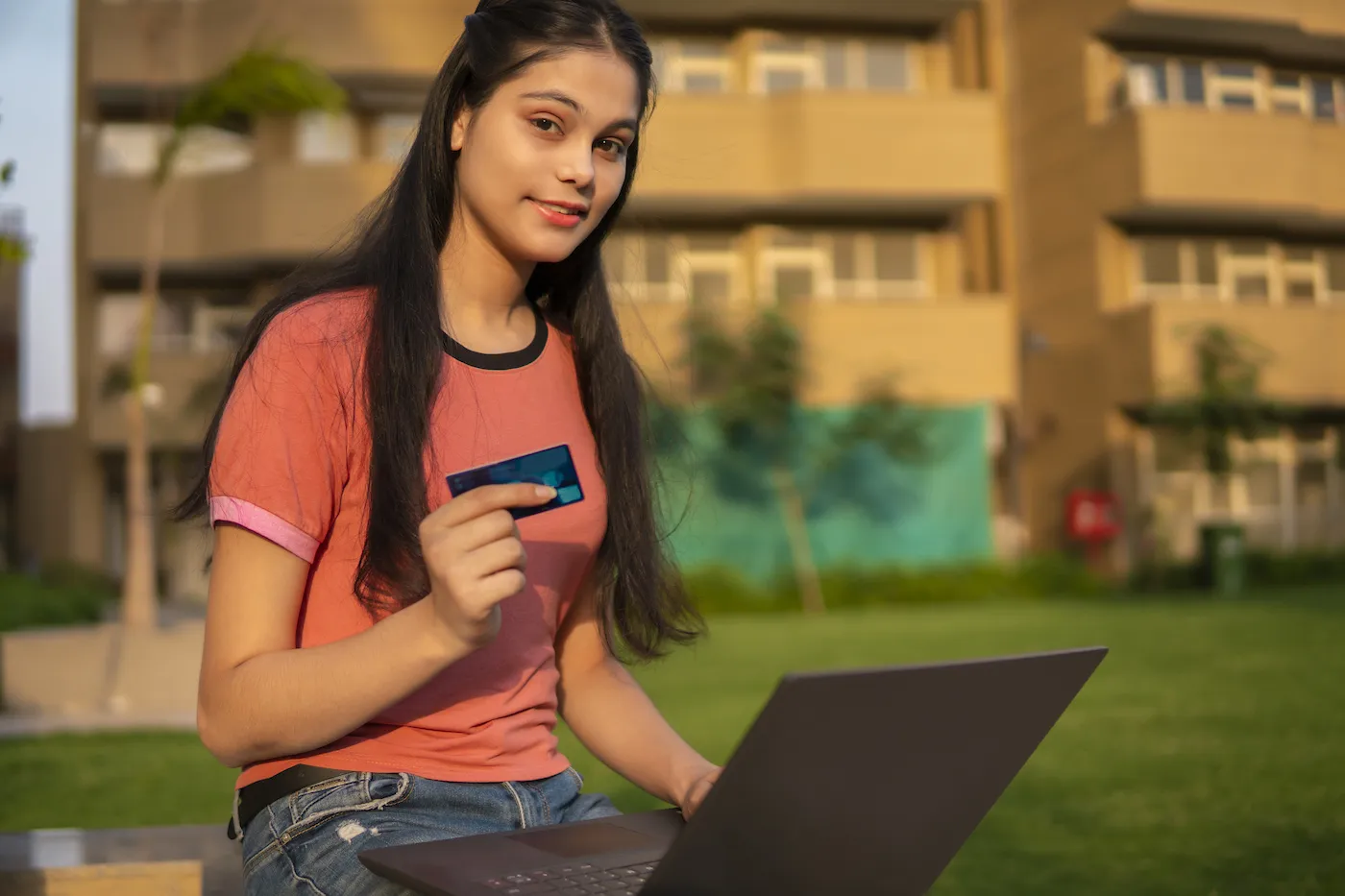 Happy student using a credit card and laptop on campus