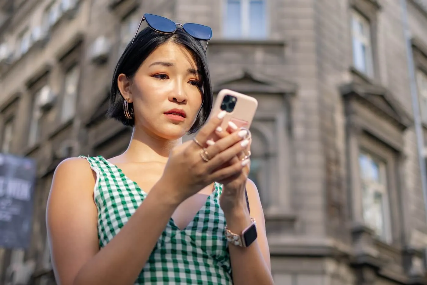 Concerned young woman checking her smartphone while walking on the street