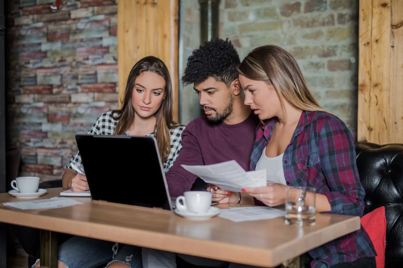 Young multi-ethnic group of students research student loans in a cafe