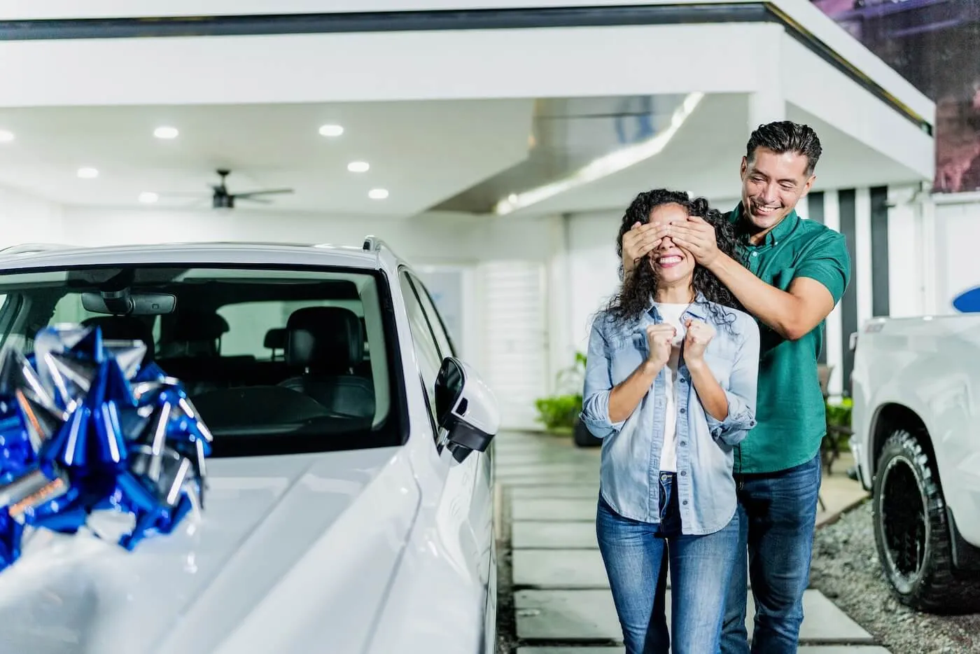 Man gifting a new car to his wife at dealership