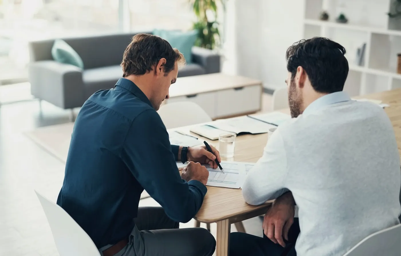 Two men discussing investing strategies at a table together.