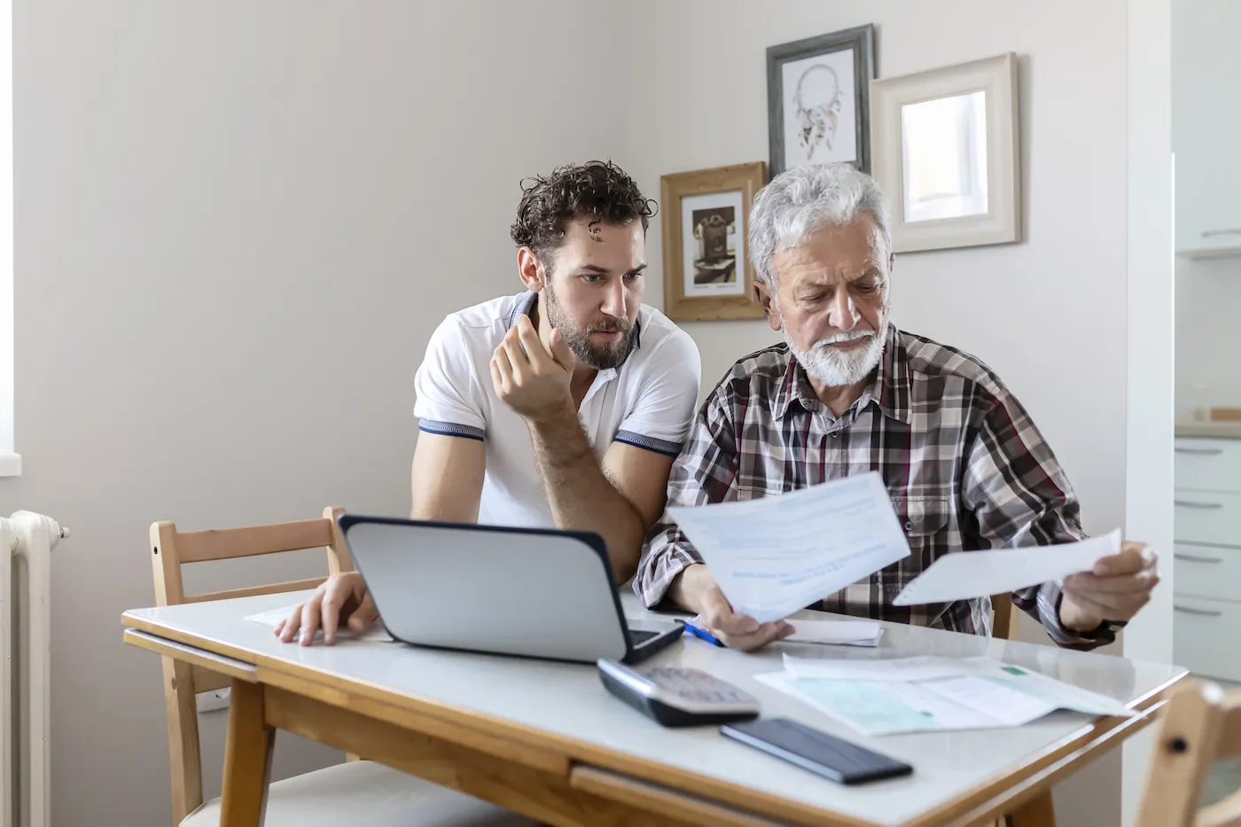 Two men sit at a table looking at finances.