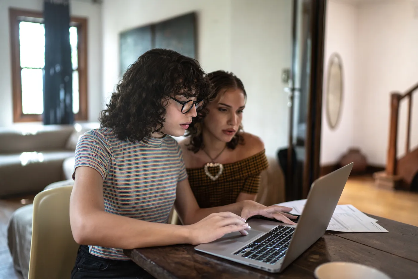 Two women researching savings accounts together on a table at home.