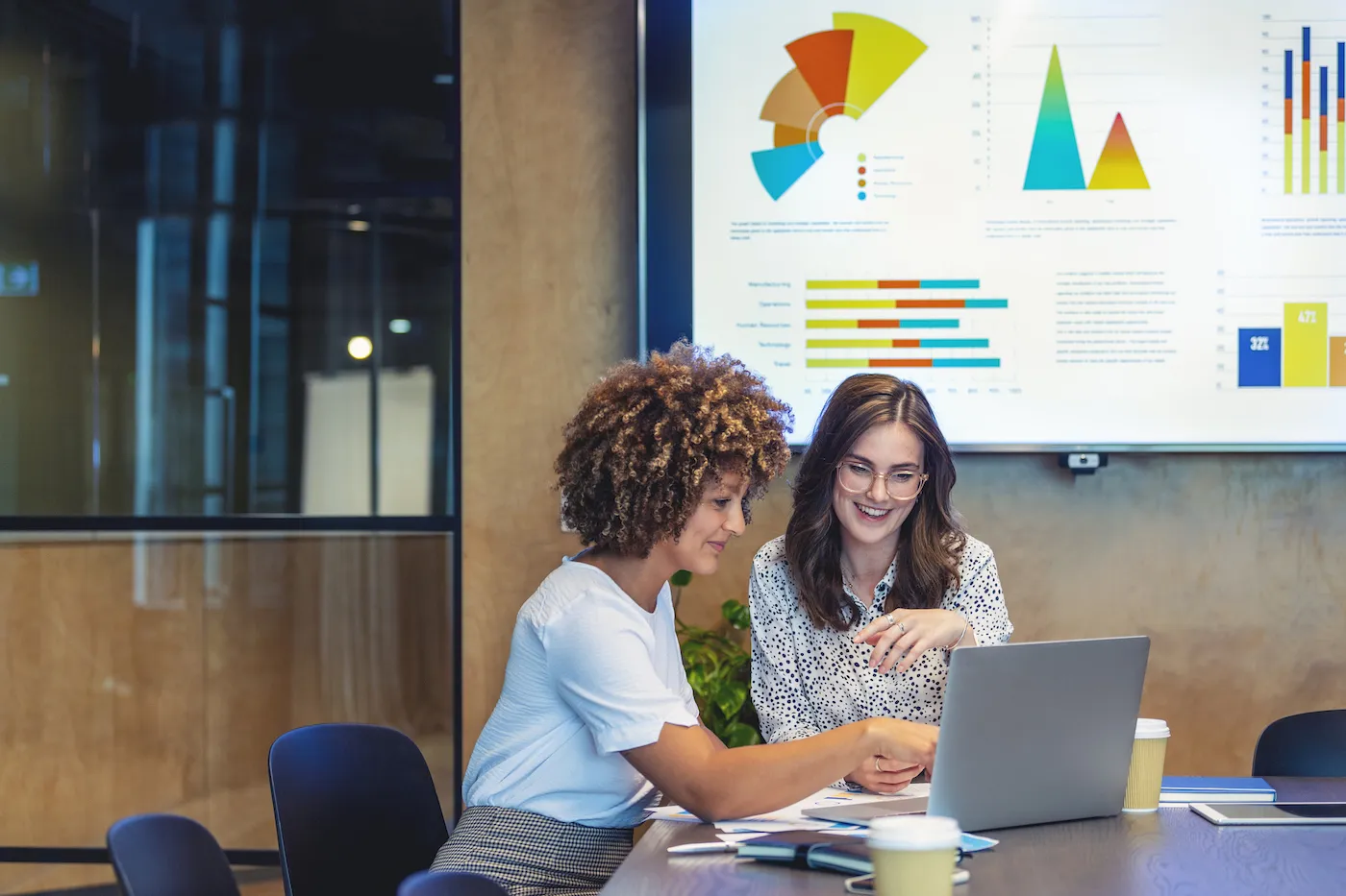 Two female colleagues going over finances together, weighing the pros and cons of money market accounts.