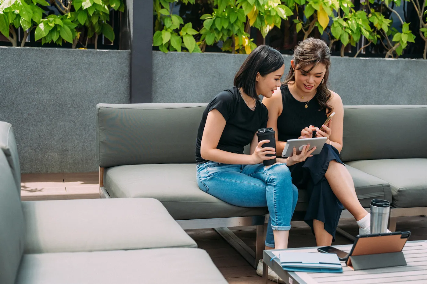 Two young women talking about their FICO scores at cozy outdoor lounge.