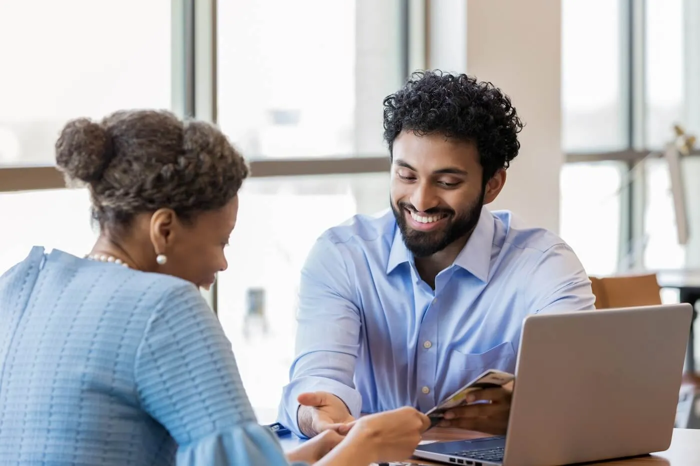 Smiling bank consultant showing a brochure to a mature female client