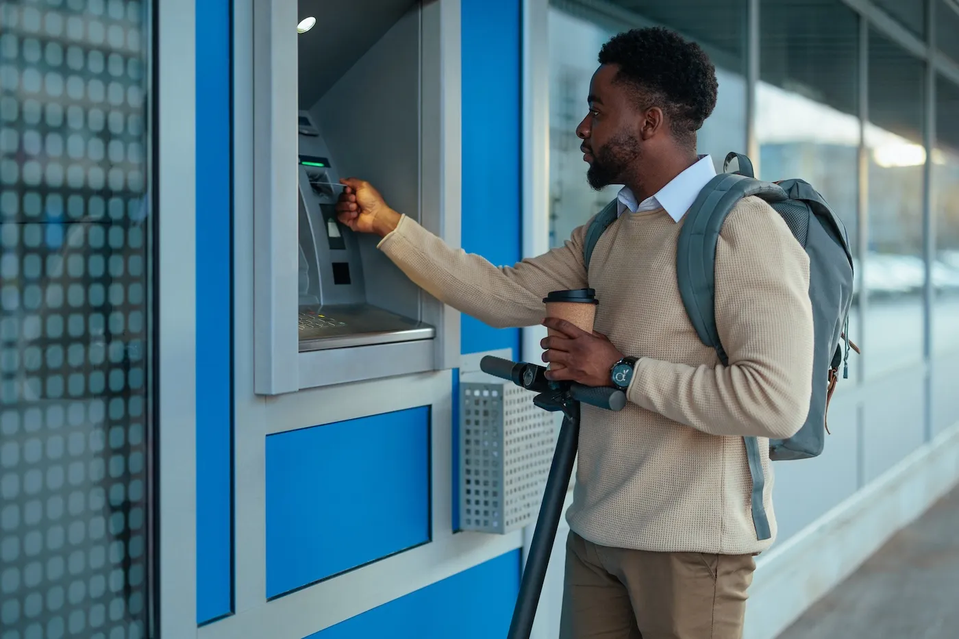 A man withdrawing from an ATM in a city setting.