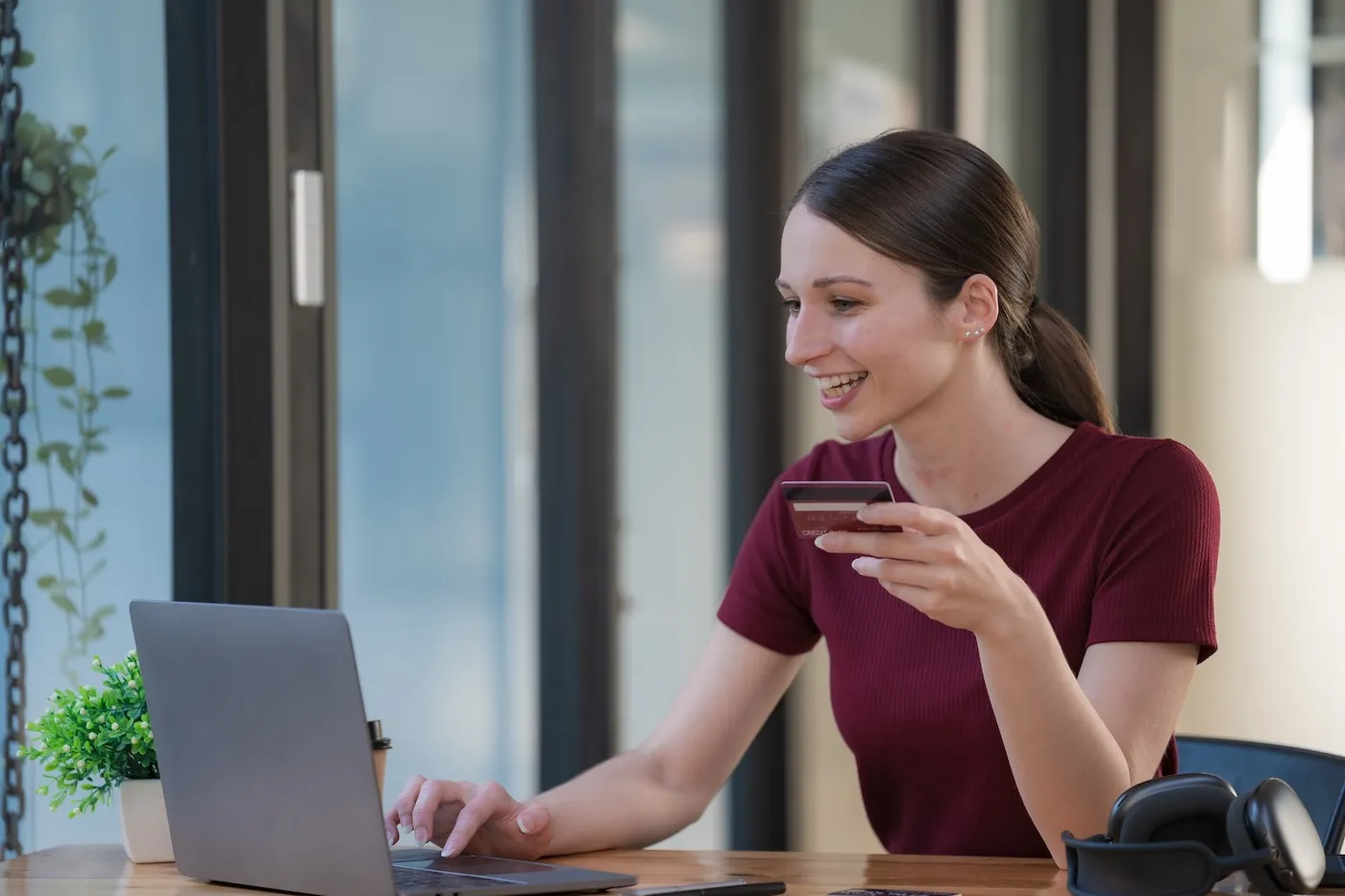 Smiling woman holding a credit card and using a laptop computer.