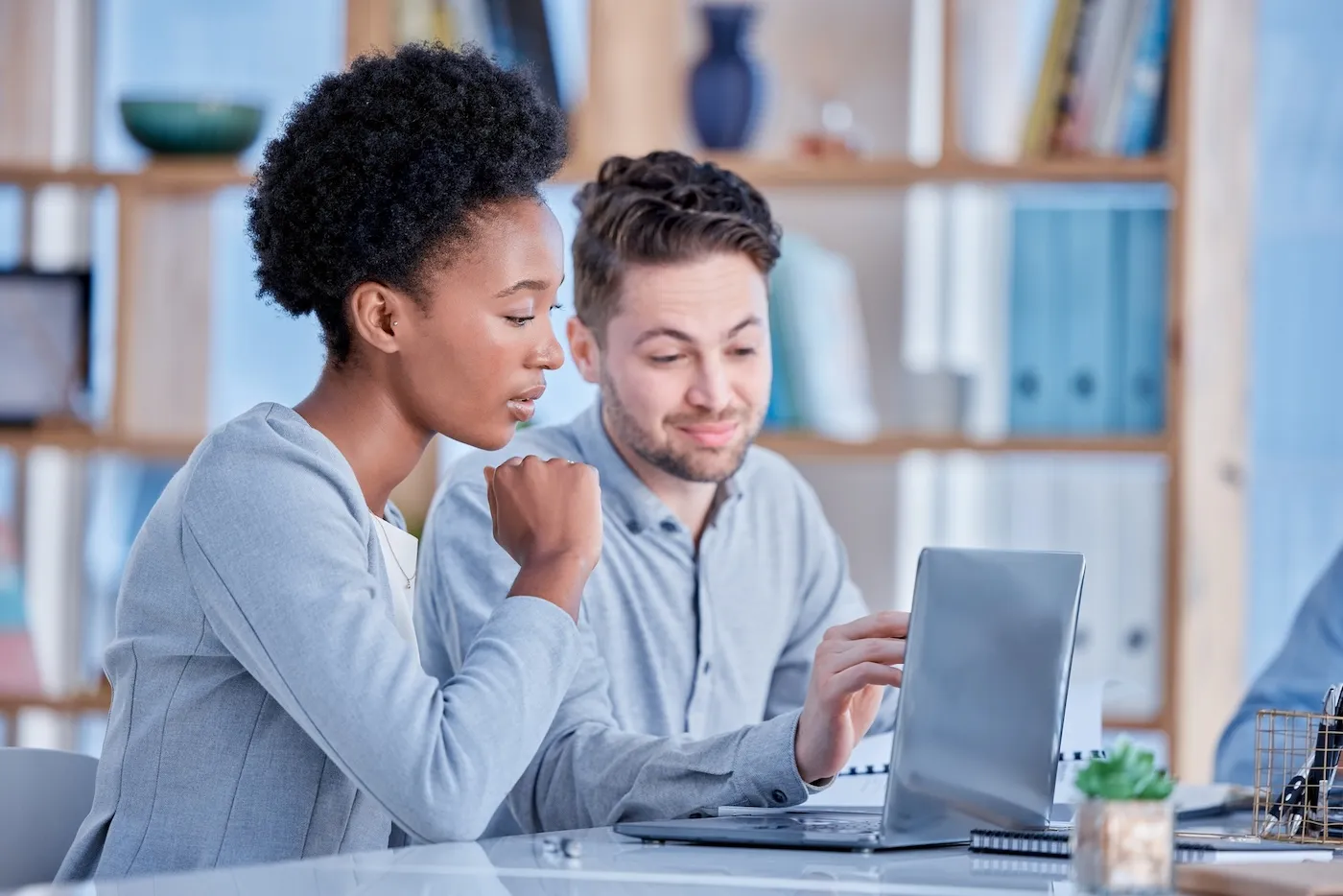 Two people reviewing finances on a computer together in an office.