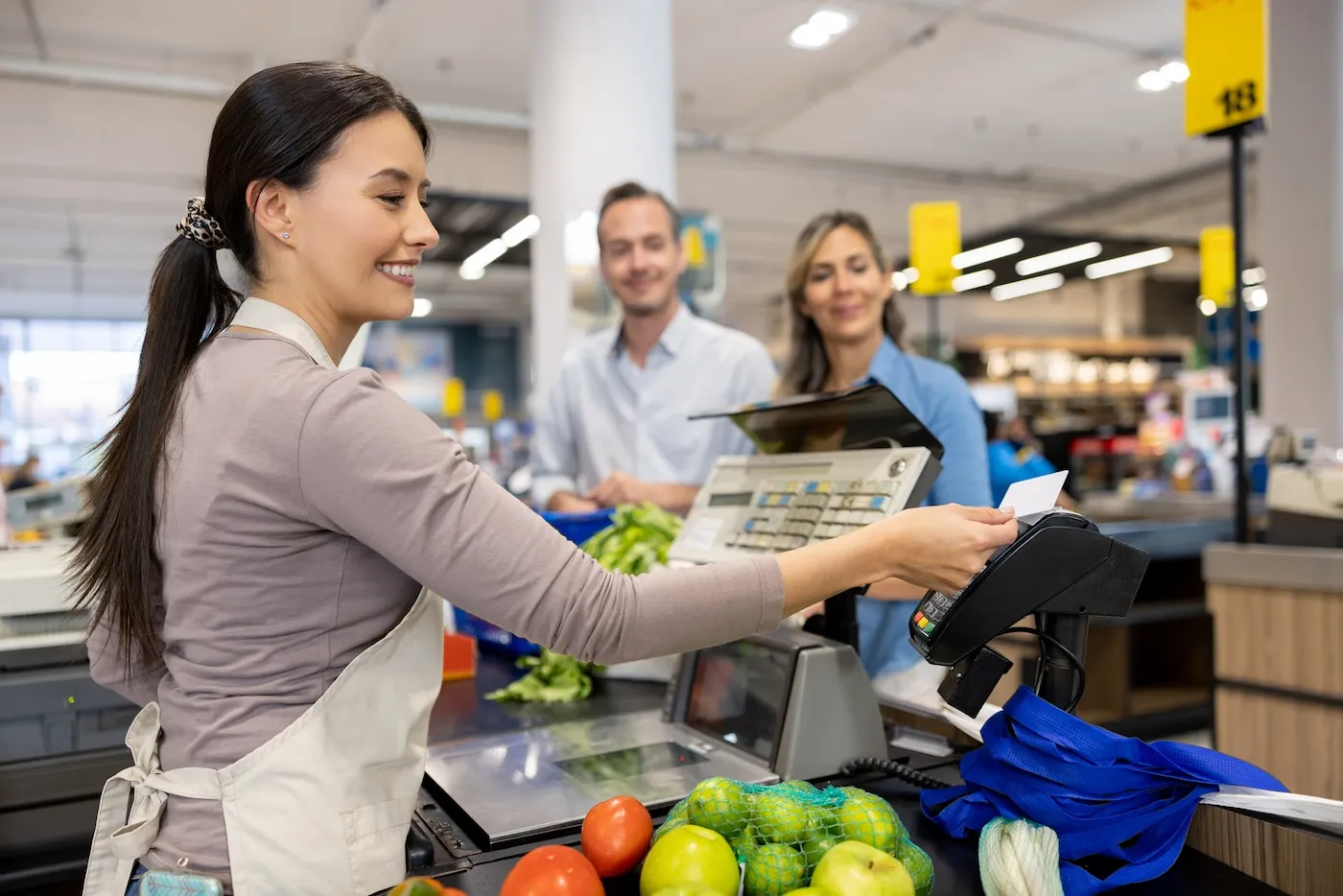 A couple shopping at the supermarket and paying by card to the cashier.