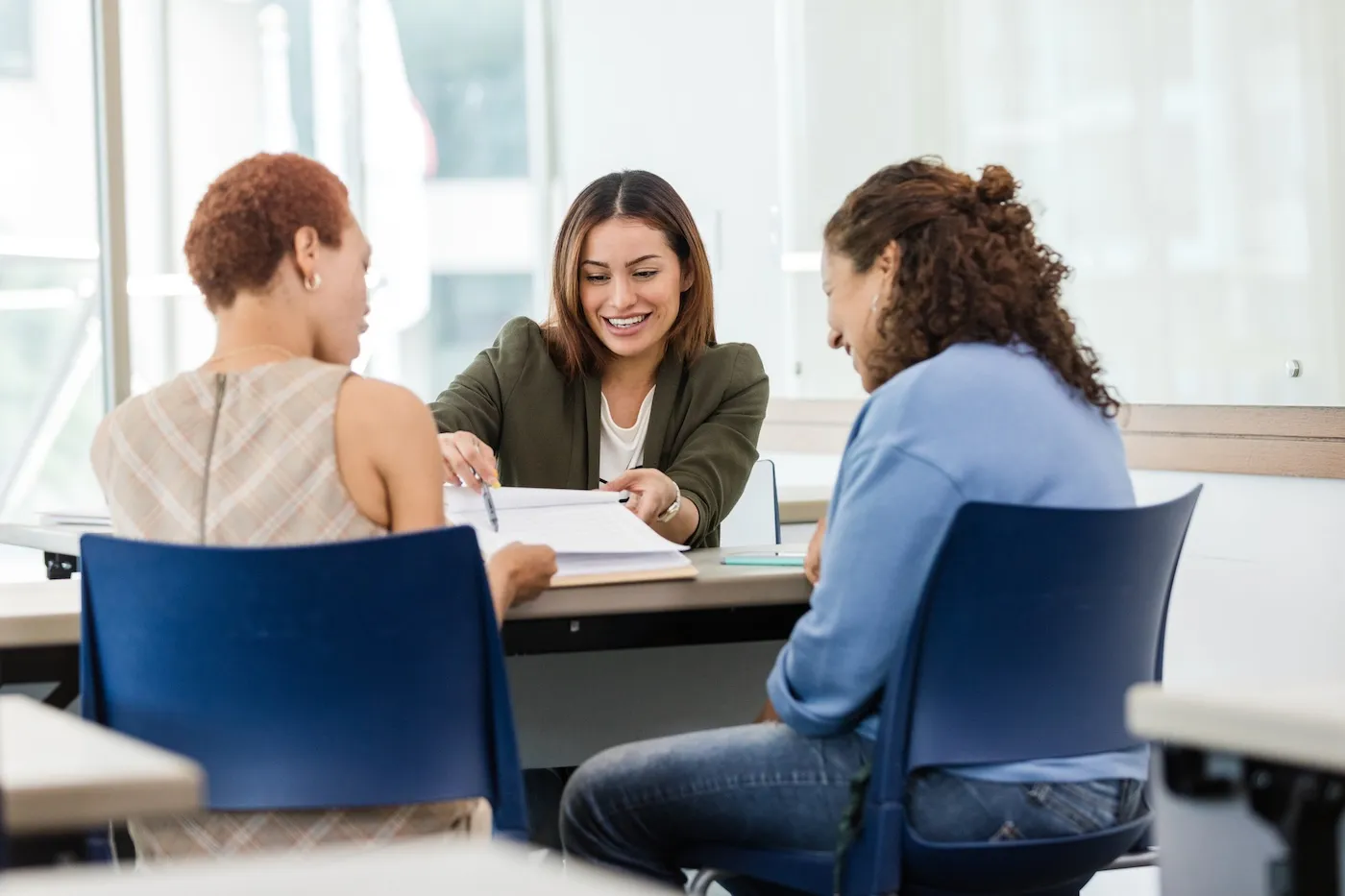 The mid adult female banker goes through the paperwork as she explains the terms to the two mid adult women.