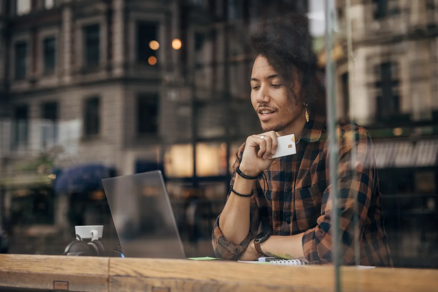 Young man using laptop in a cafe, shopping online with credit card.