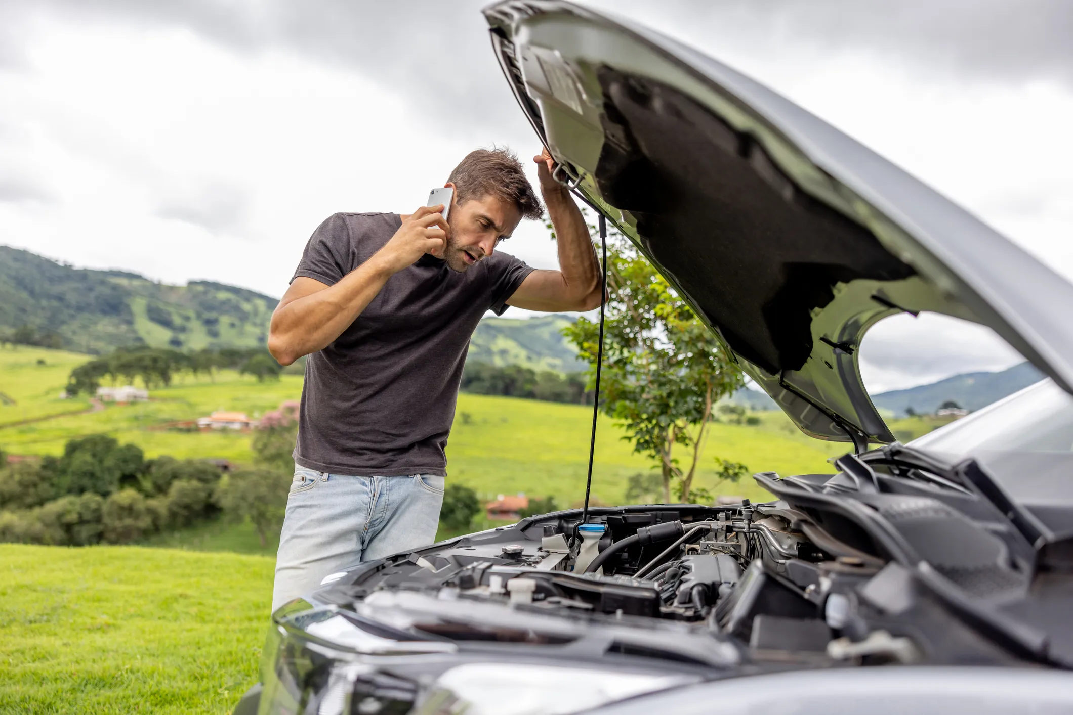 A man calling roadside assistance after having a vehicle breakdown on the road.