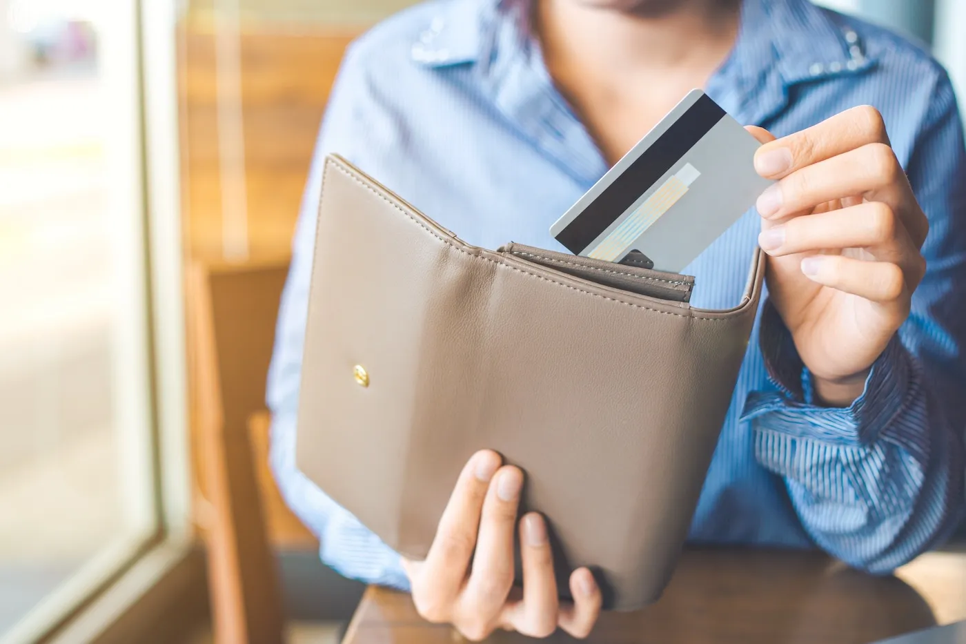 Women's hand putting a credit card card in her wallet.