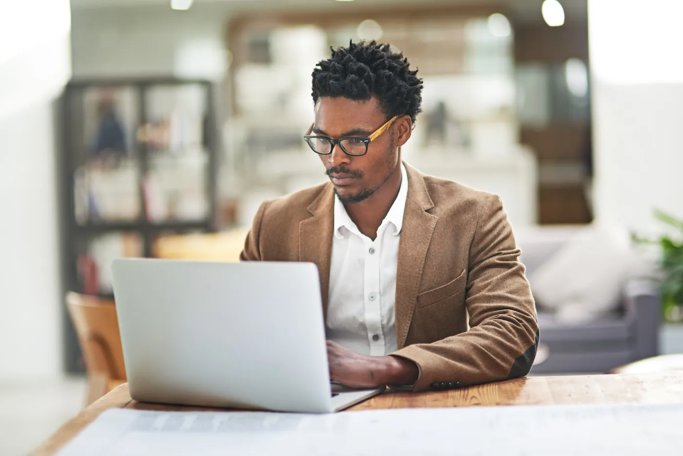 Cropped shot of a young man working on his laptop at his desk in his office.