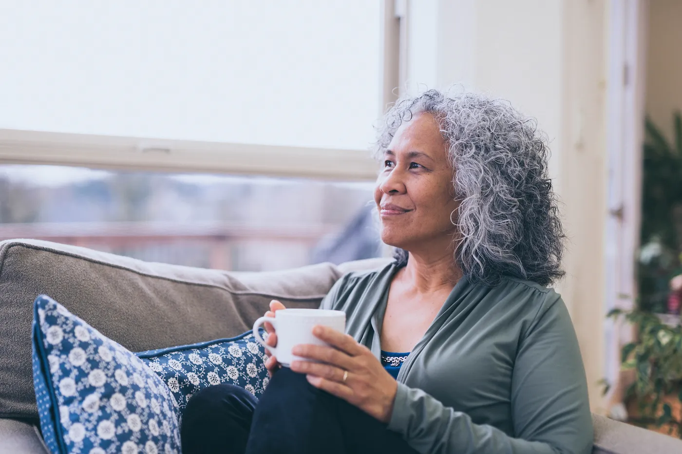 Happy retired woman drinking coffee inside in the morning.