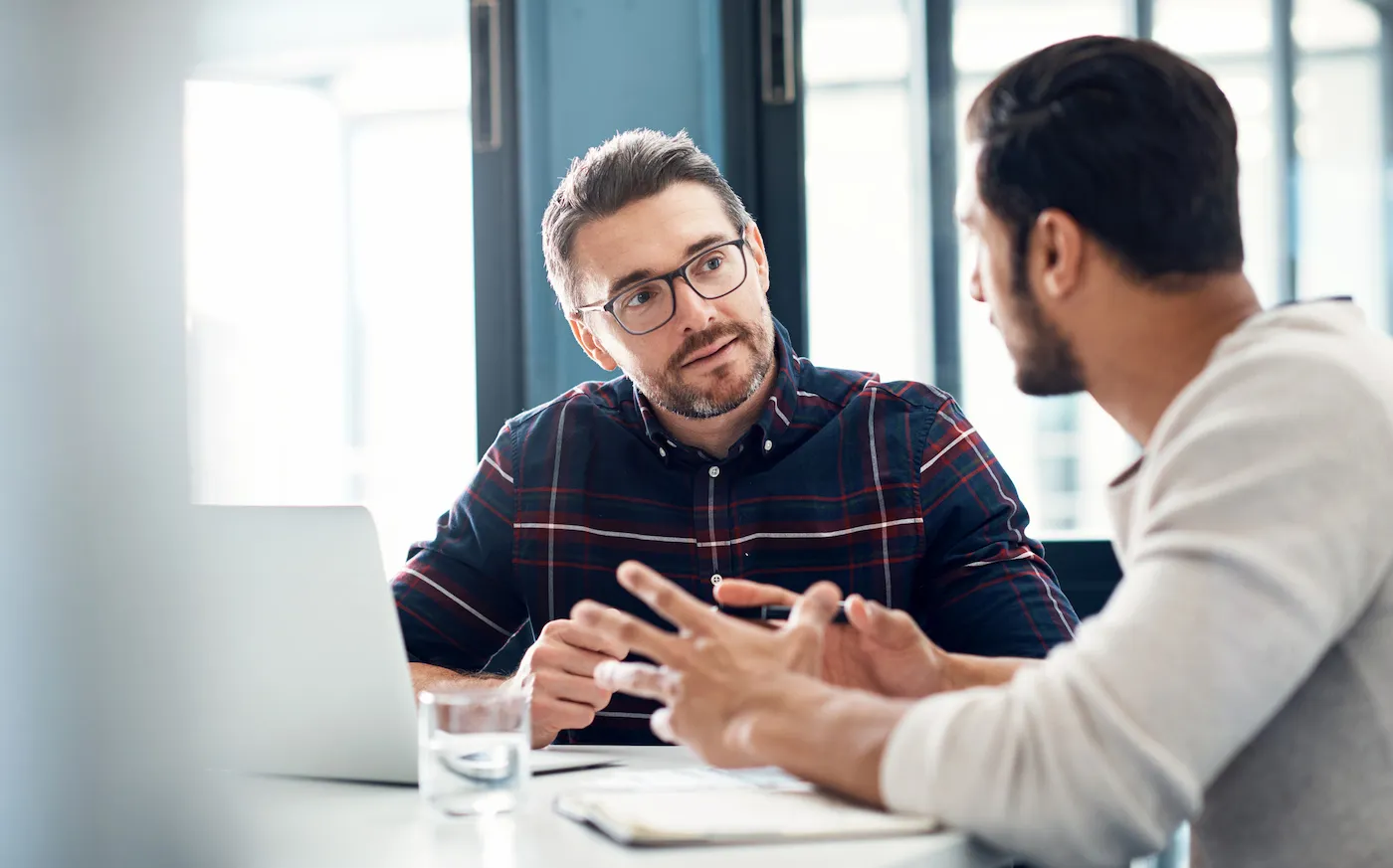 Shot of two men having a discussion in an office about getting a bridge loan.