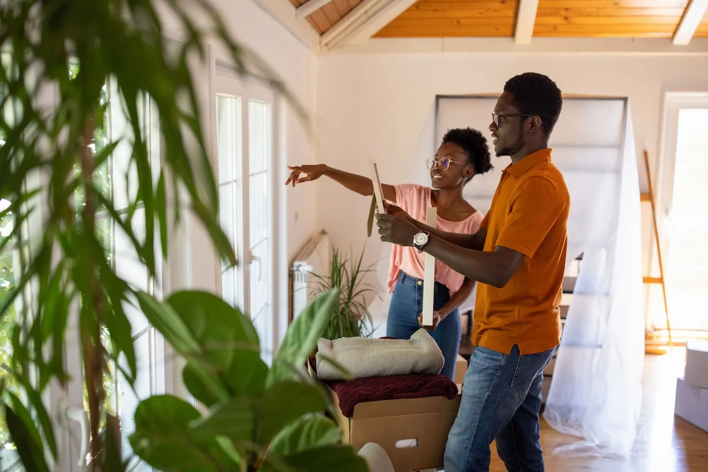 Two people arranging pictures on the wall in their new apartment.