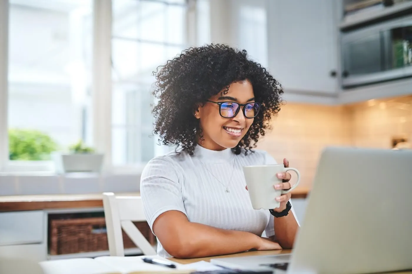 Smiling woman working on the laptop while drinking coffee