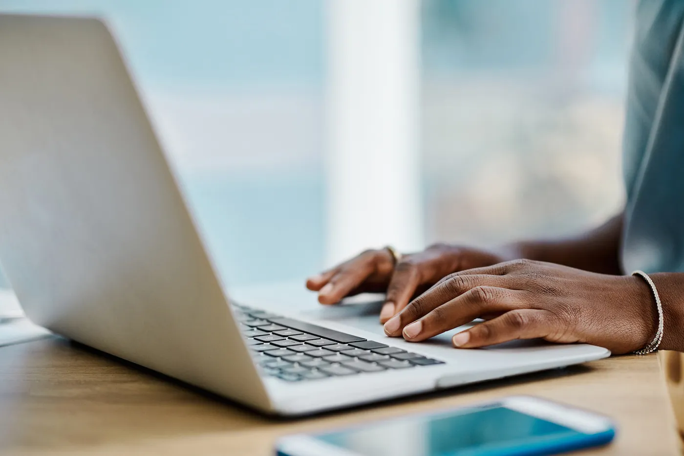 Hands browsing on a laptop in an office alone