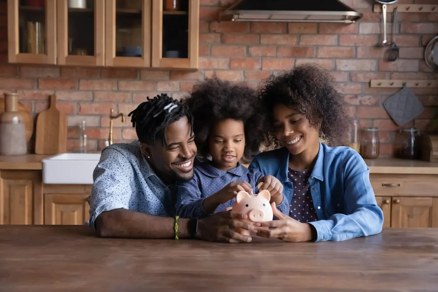 Happy family with a toddler girl holding a piggy bank in the kitchen