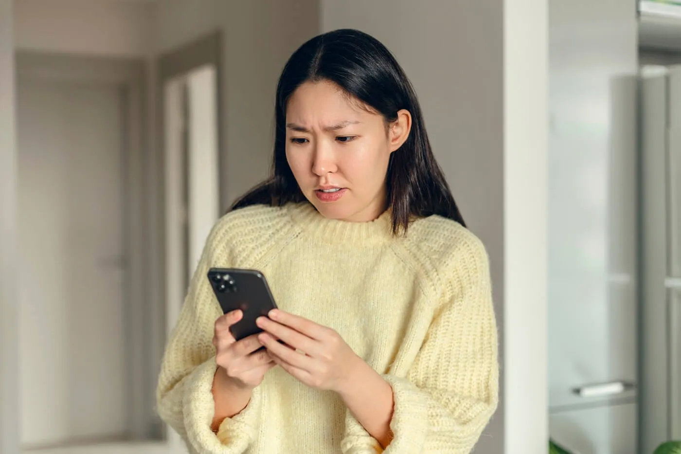 Concerned young woman looking at her smartphone screen