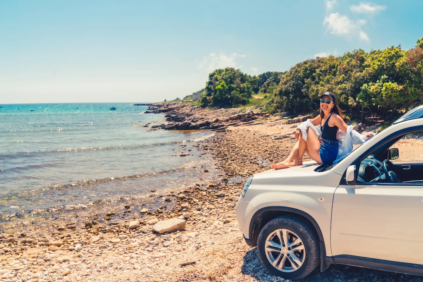 A woman laying at car hood with view of sea