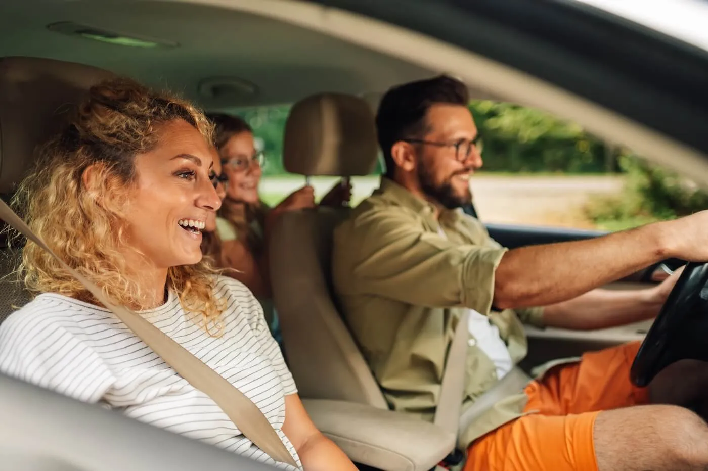 Happy family of three sitting in the car