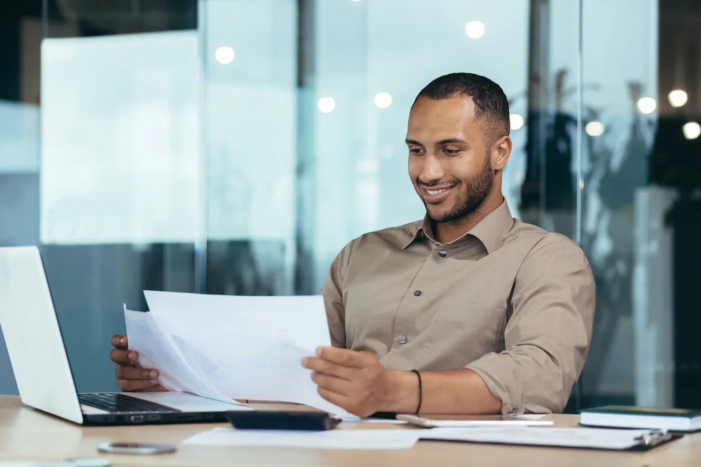 A man inside the office reading an income statement, working on a laptop.