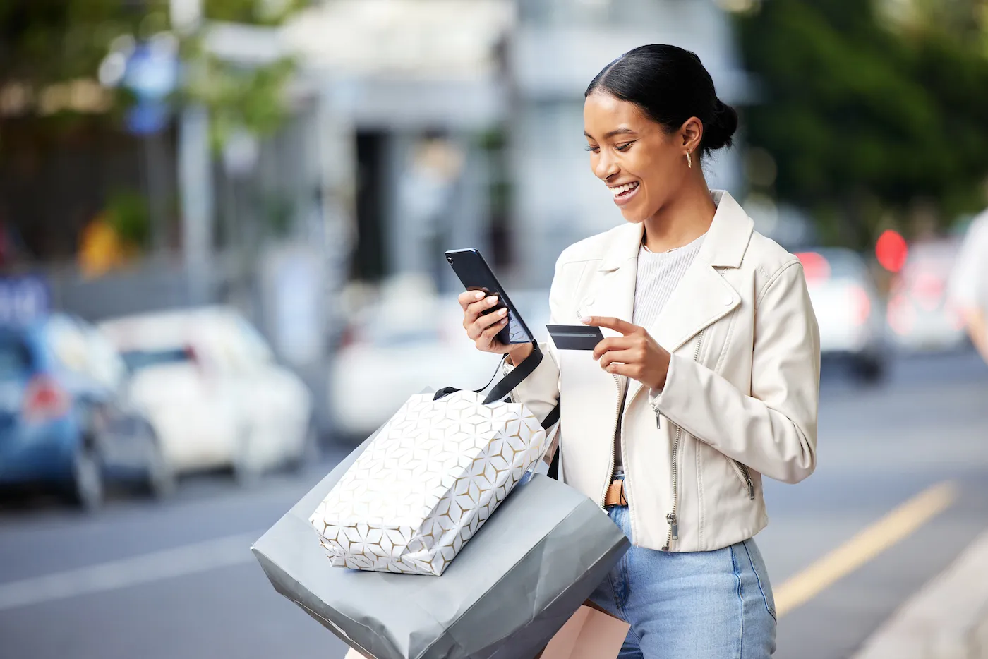 Happy woman with her phone, credit card and bag after shopping in the city.