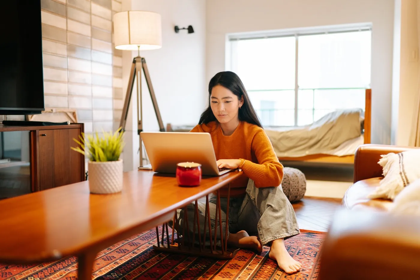 A young woman is using a laptop comfortably in the living room at home.