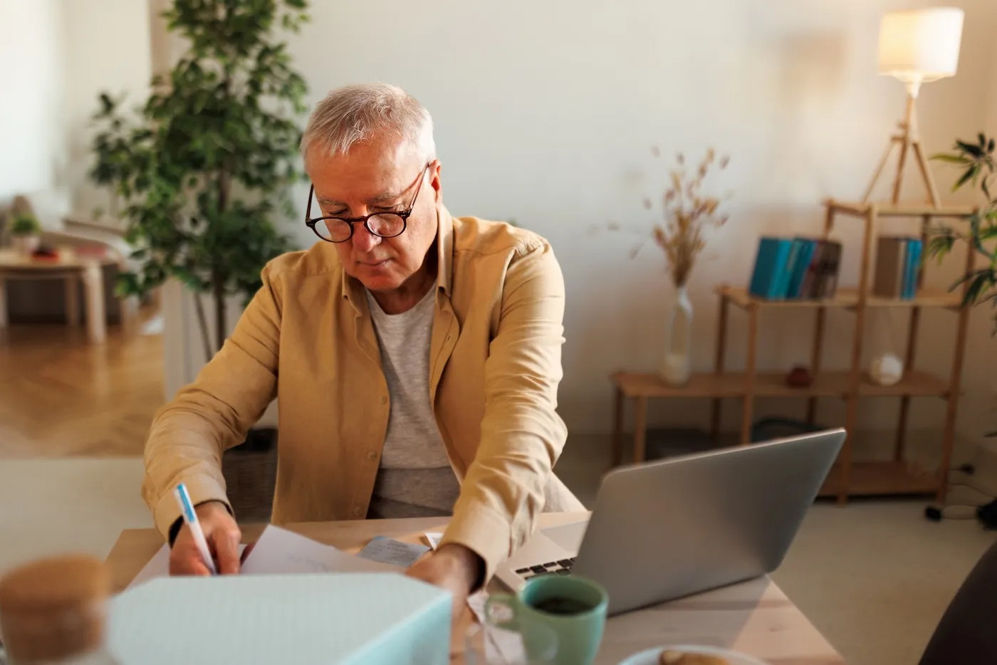 Senior man using laptop checking documents.