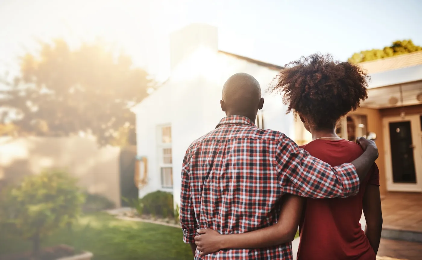 Rear view shot of a young couple admiring their new house outside