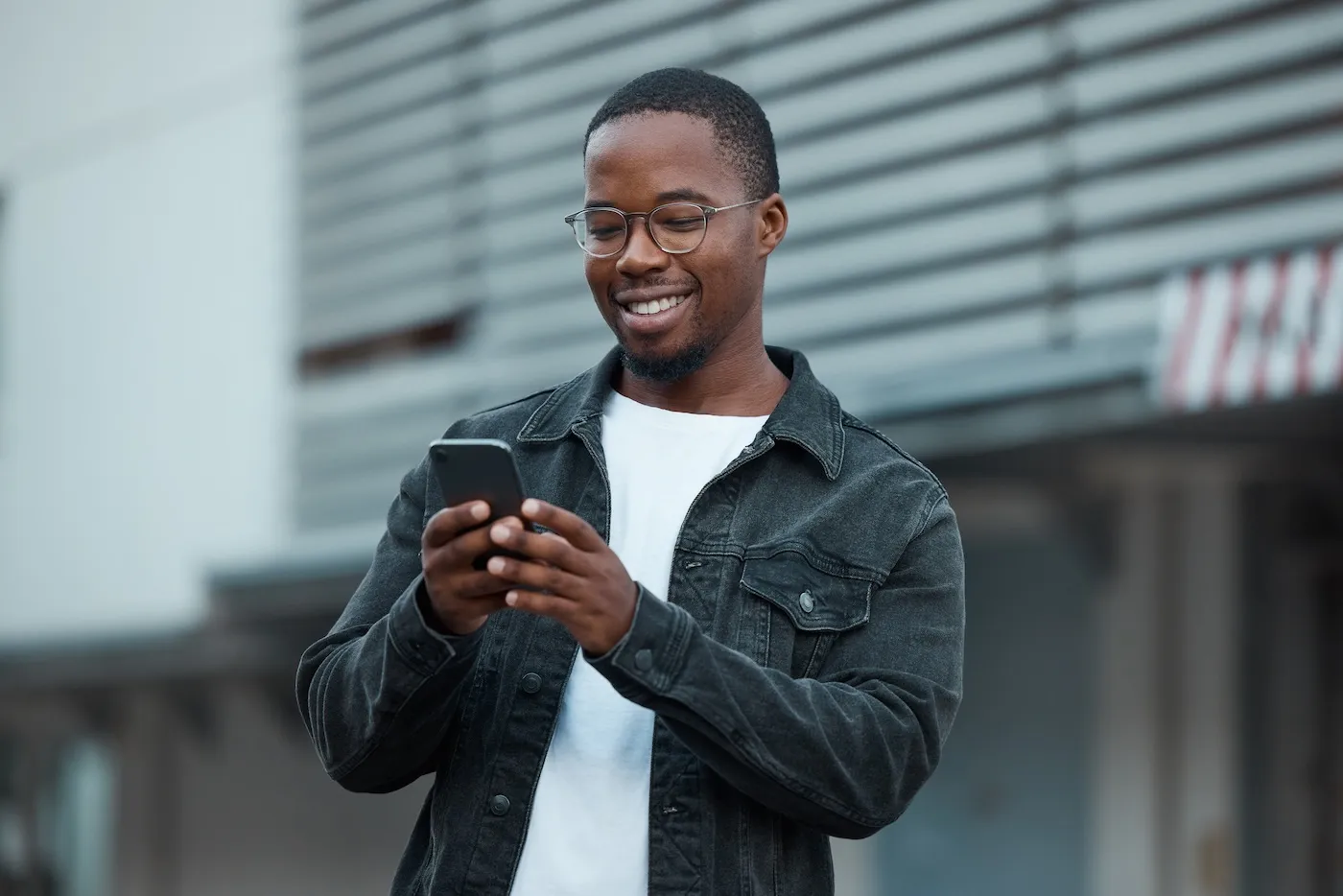 A man looking at his phone while walking in the city.