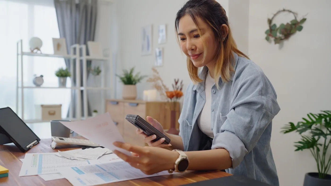 Woman uses smartphone for managing her personal finances at home.