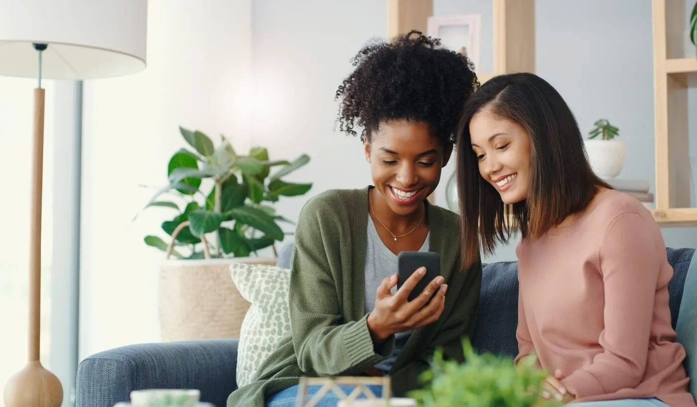 Two smiling young women looking at the smartphone screen