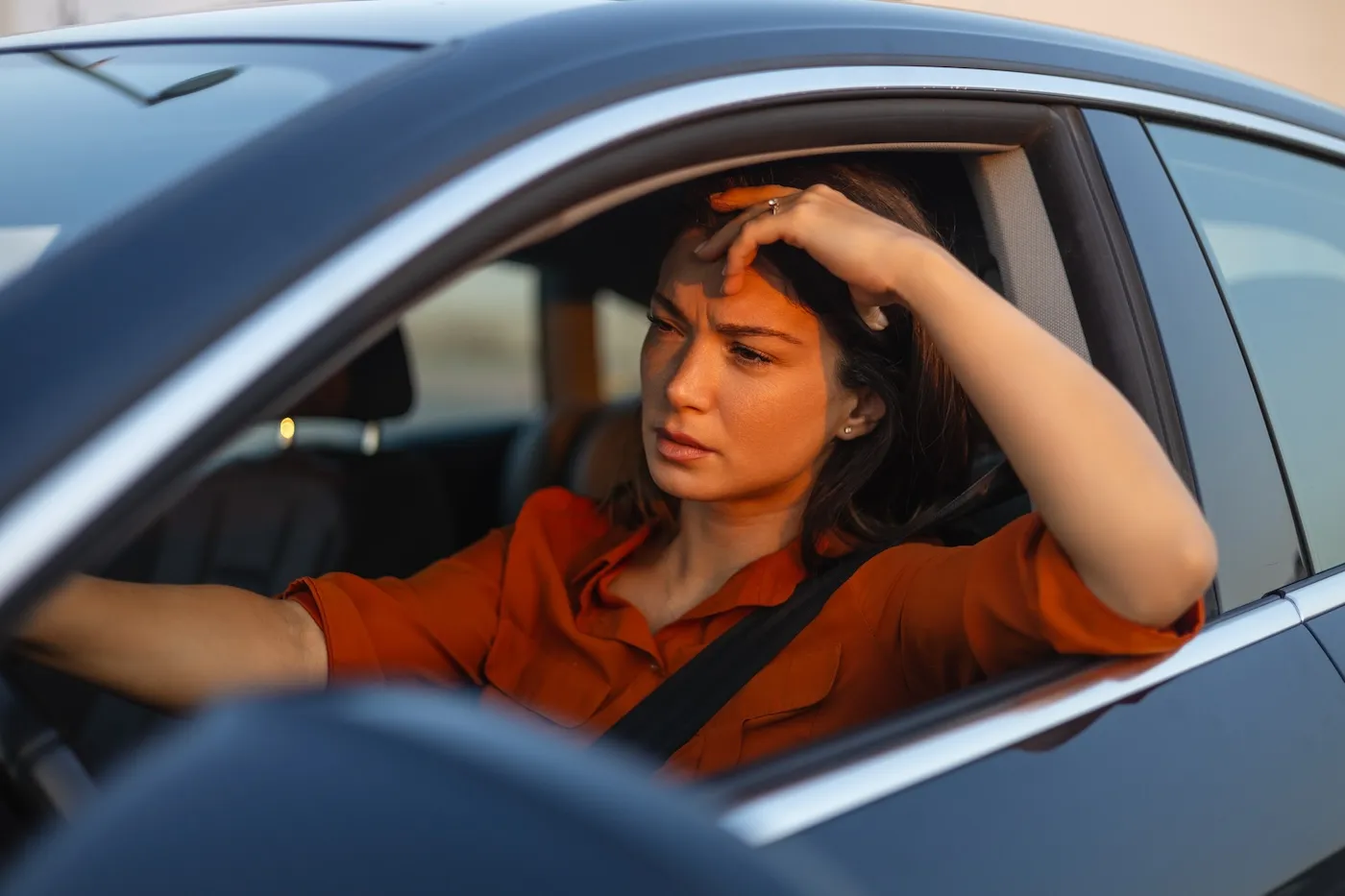 Stressed young woman driver sitting inside car.