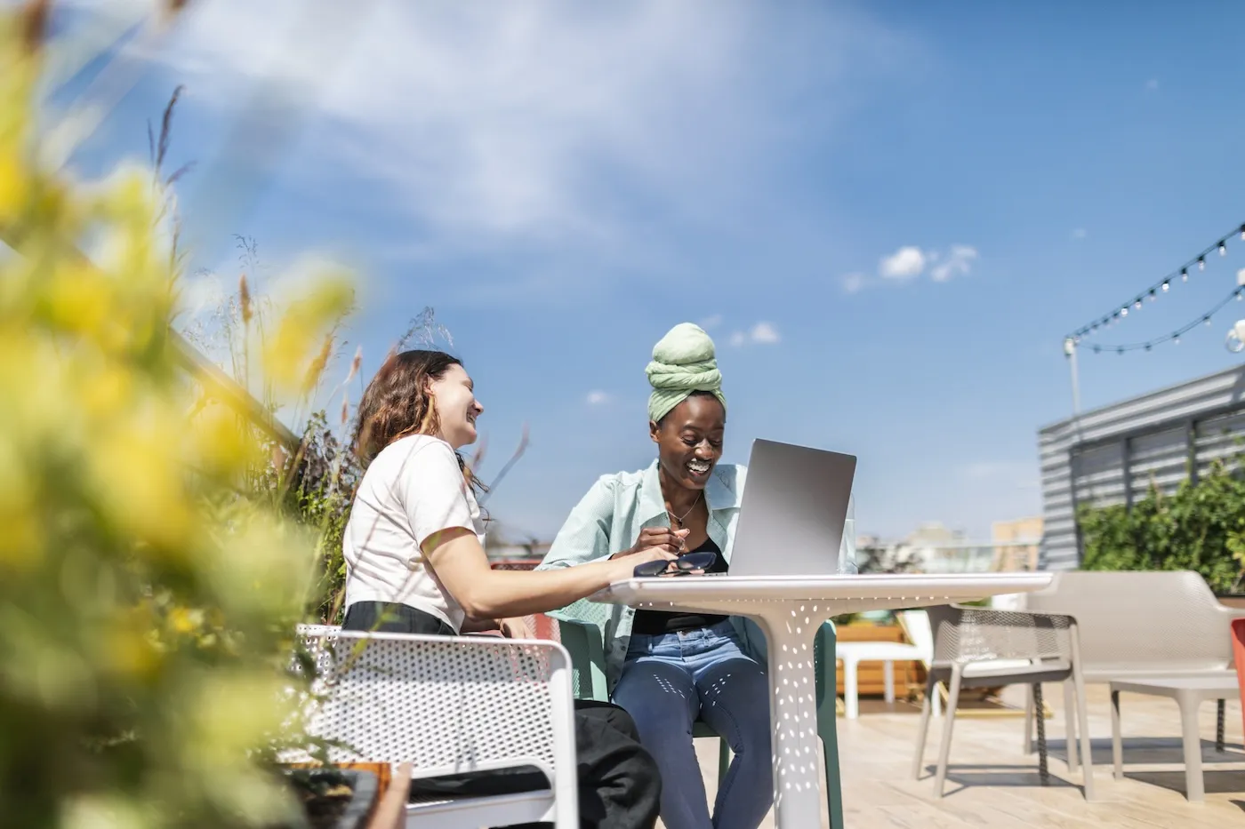 Two young adult women discussing finances at outdoor cafe.