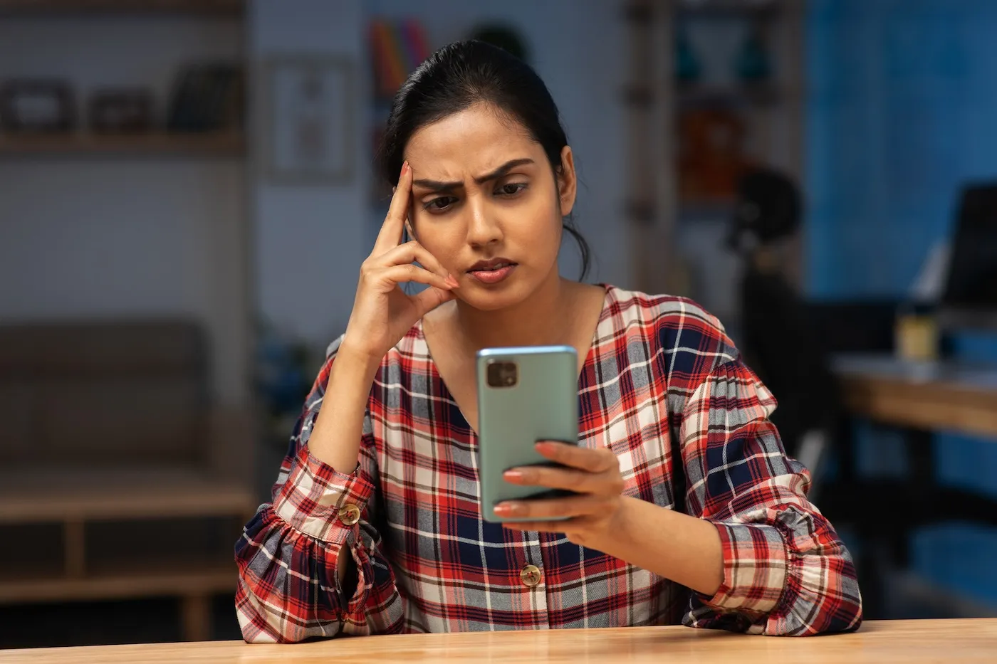 Concerned woman looking at her phone at home.