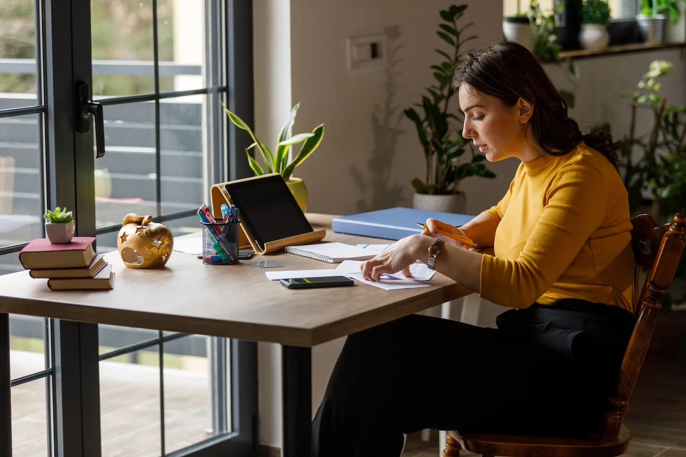 Shot of diligent young woman sitting at home office desk, deciding where to keep her emergency fund.