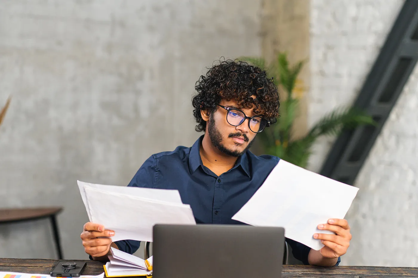 A man doing paperwork while sitting at a desk with laptop in office.