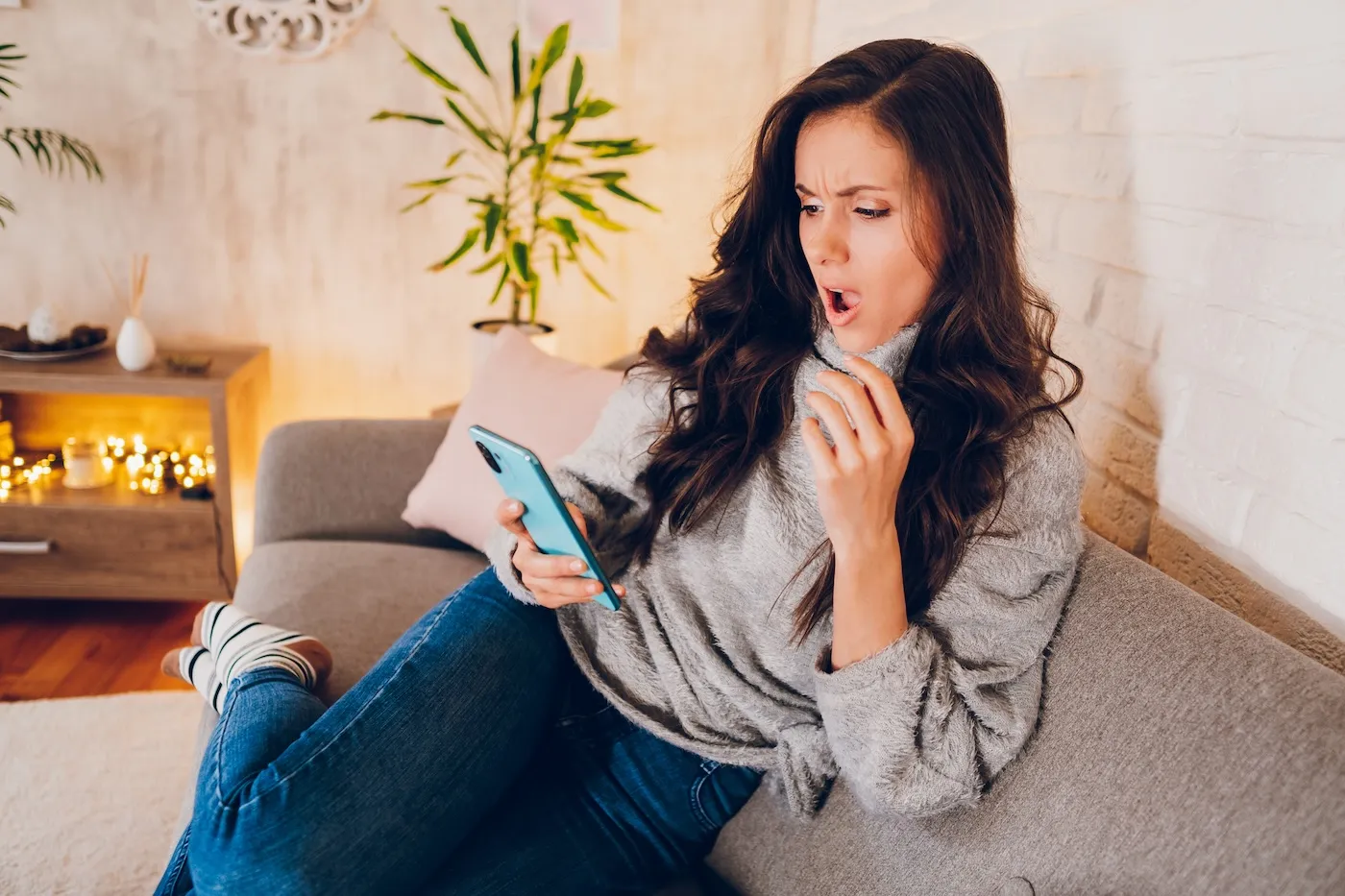 A young shocked woman looking at mobile phone.