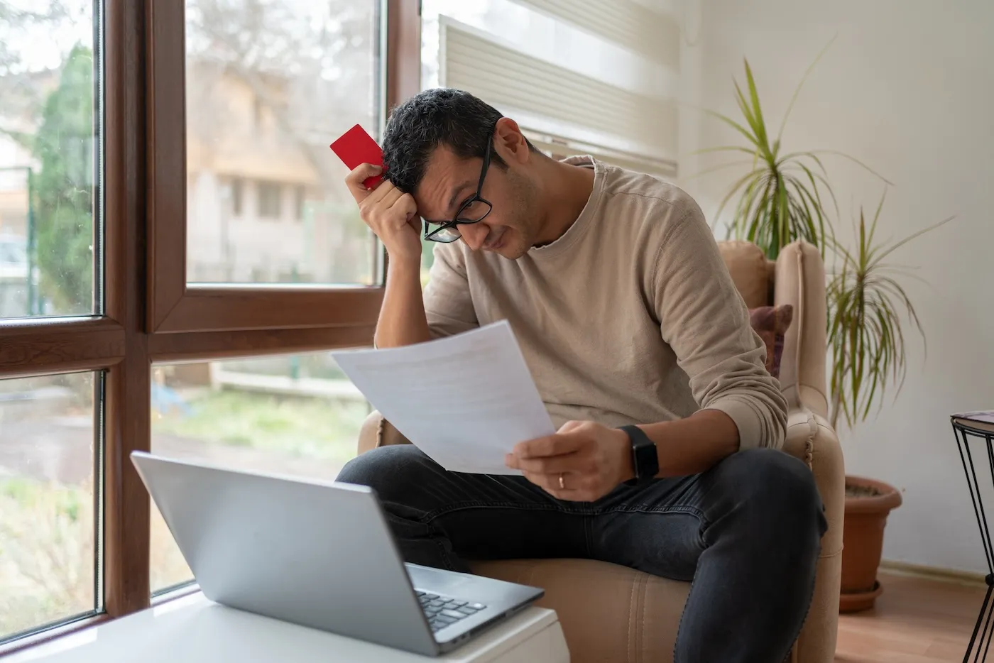 A man reading a letter and holding a credit card.