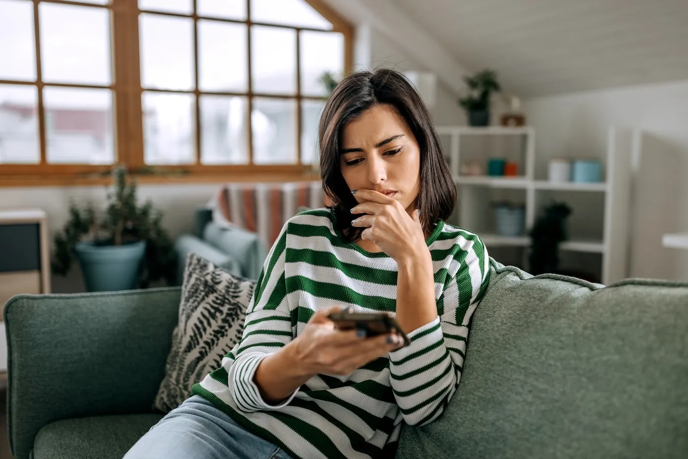 Concerned young lady looking on smartphone screen having finance issues.