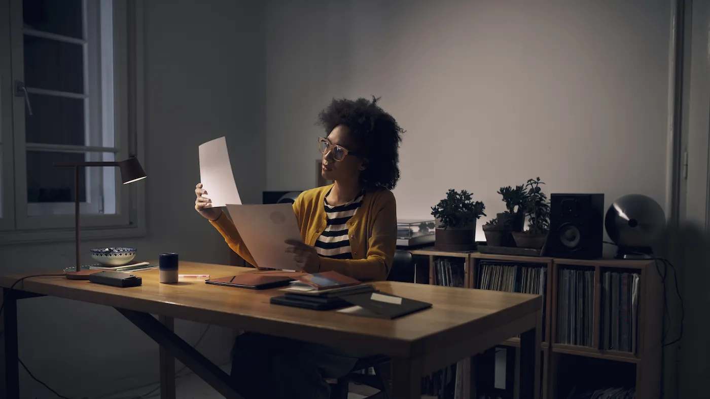 Businesswoman looking over papers t her desk at night.