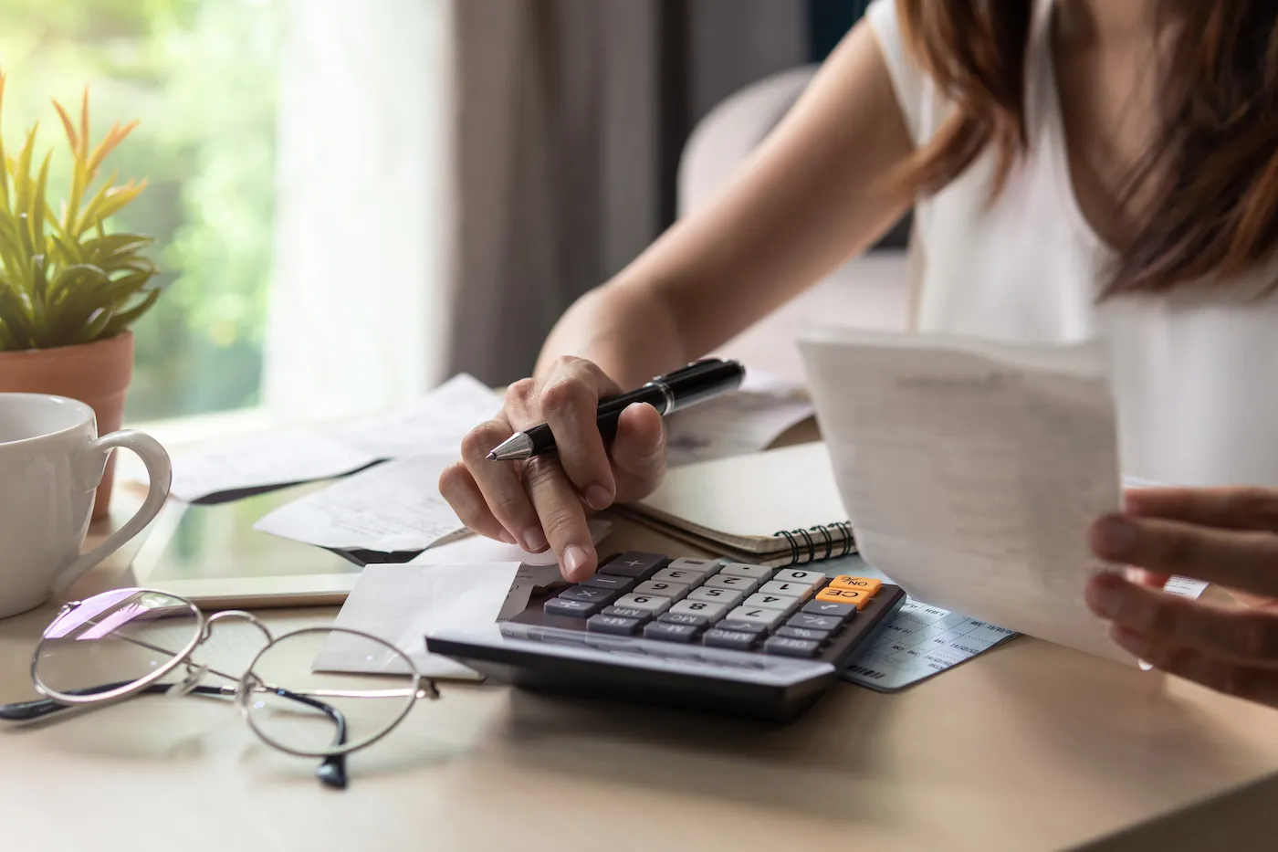 Stressed young woman checking bills, taxes, bank account balance and calculating expenses in the living room at home